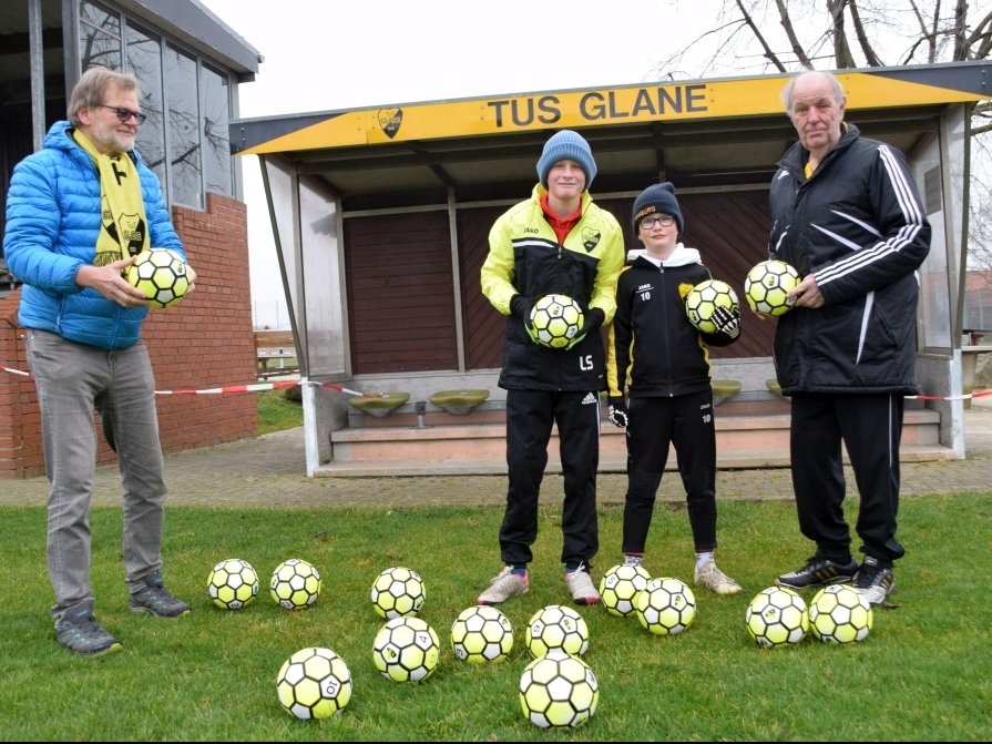 Bild: TuS Glane Vorsitzender Fritz Wellmann (li.) überreicht Fußballobmann Franz Buchholz (re) und Linus und Fabio Schmitz 30 Fairtrade Bälle für die Spieler der U5 und U6 des Vereins.